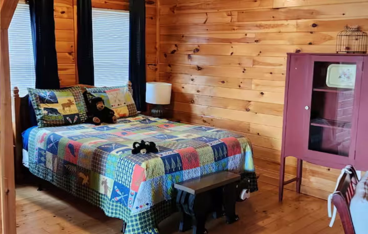 Queen bedroom with lodge quilt and pine walls