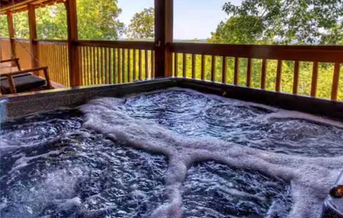 Hot tub on the covered deck with a treeline view