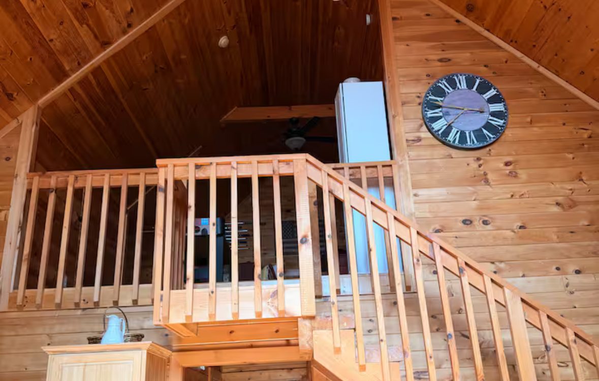 Open loft with wood railing and vaulted pine ceiling